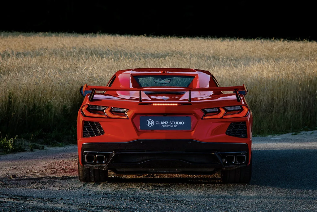 Tył Corvette C8 z tablicą Glanz Studio, w tle łan zboża