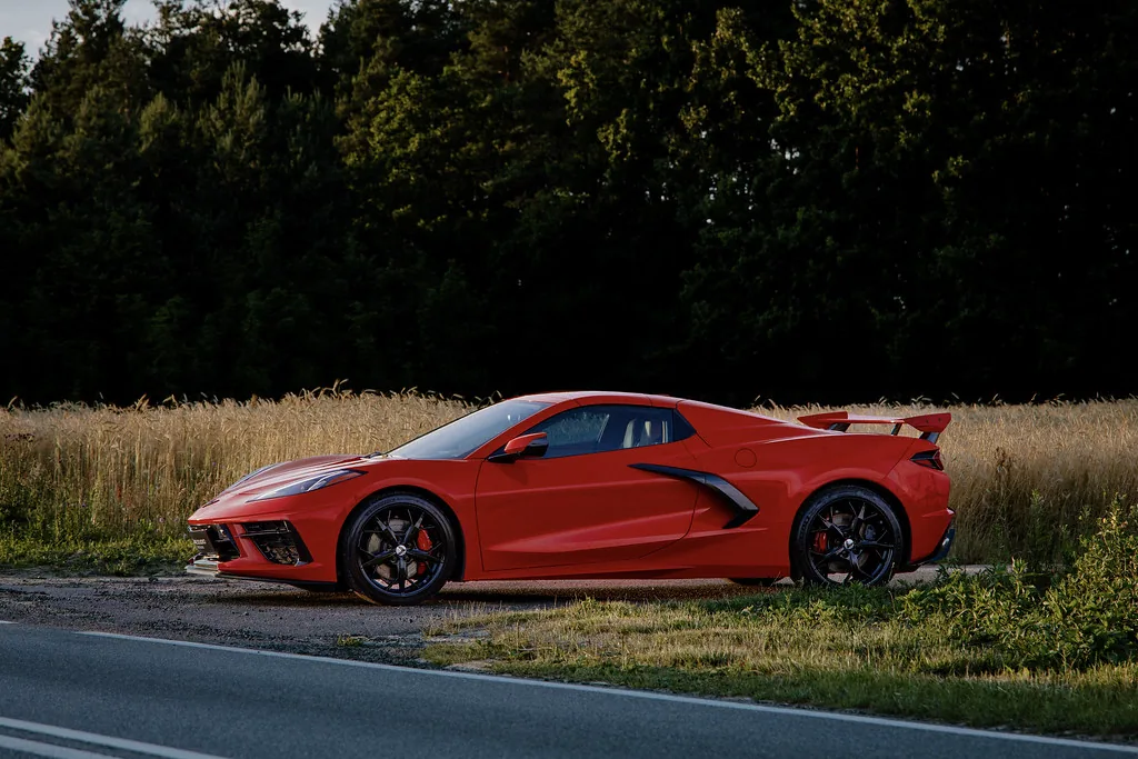 Corvette C8 z profilu na tle ciemnych drzew i pola