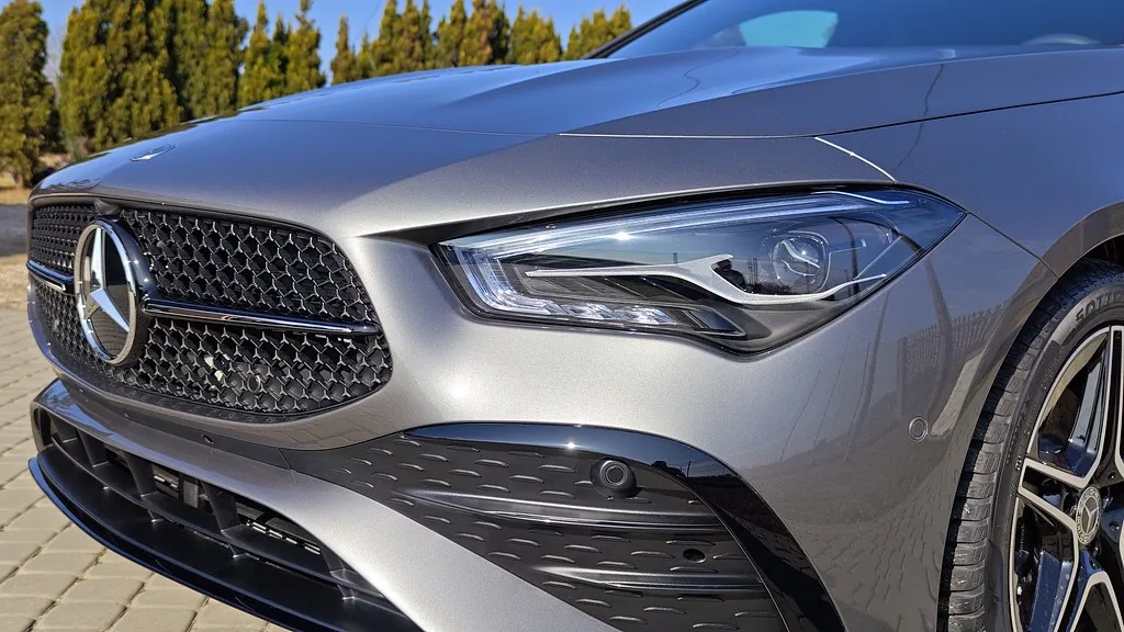 Zbliżenie na grill i reflektor Mercedesa CLA, lustrzane odbicia w lakierze